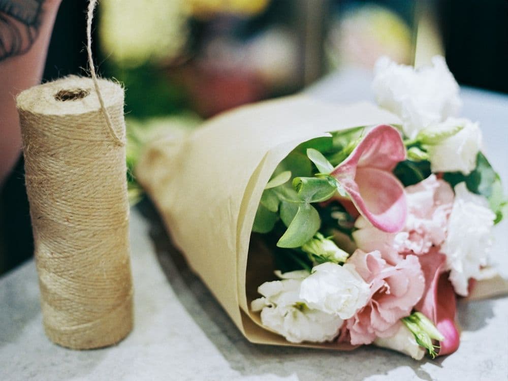 A hand-tied bouquet in kraft paper beside a spool of twine