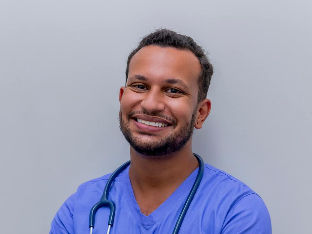A smiling chiropractor in blue scrubs