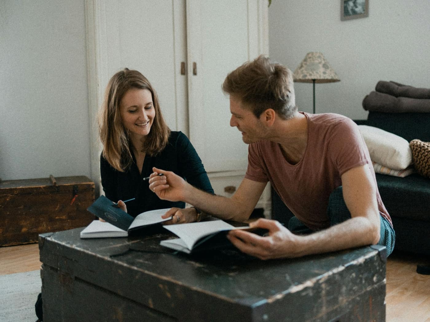An interior designer going through a notebook with a couple on a sofa in a studio