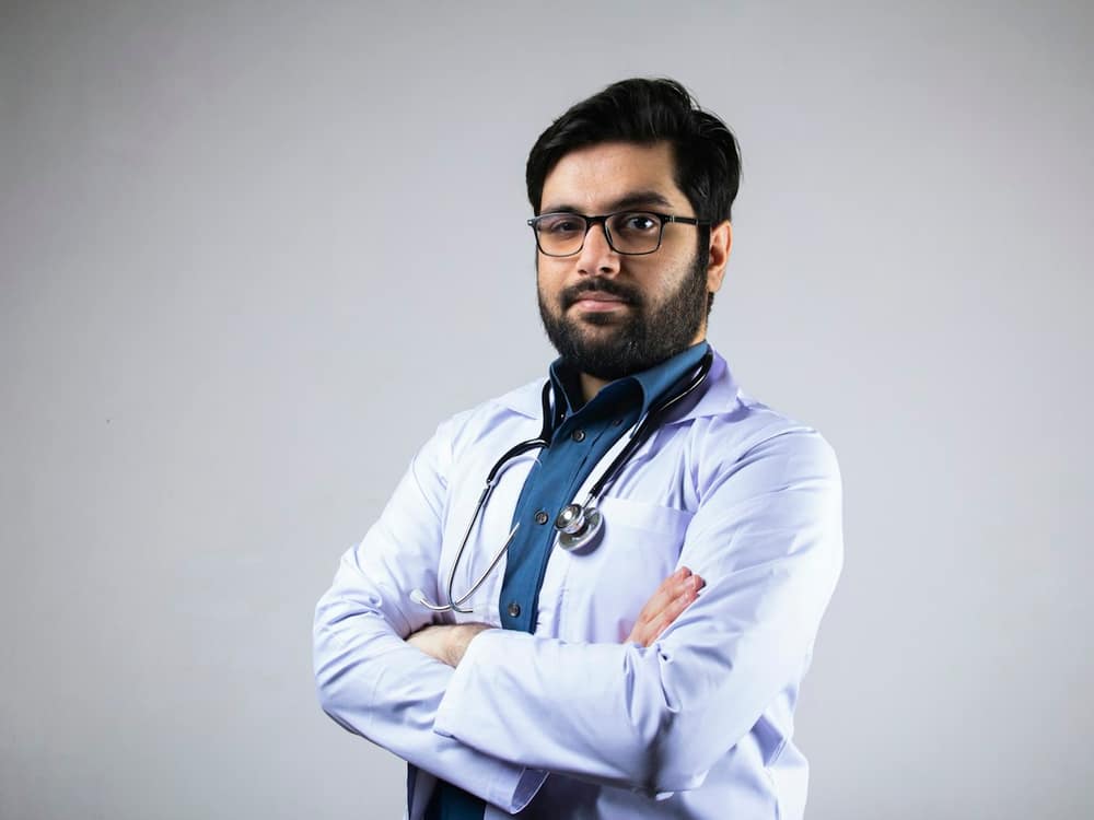A paediatrician in glasses and a white coat, arms folded