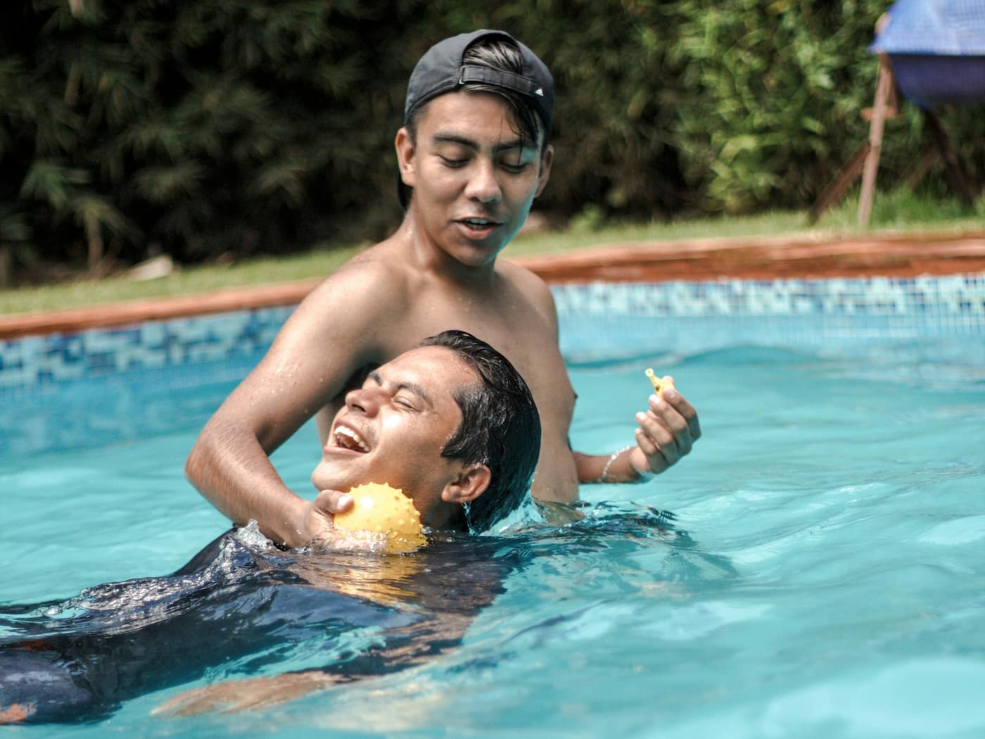 A swim coach in the water with a smiling adult learner, both holding on to a foam float