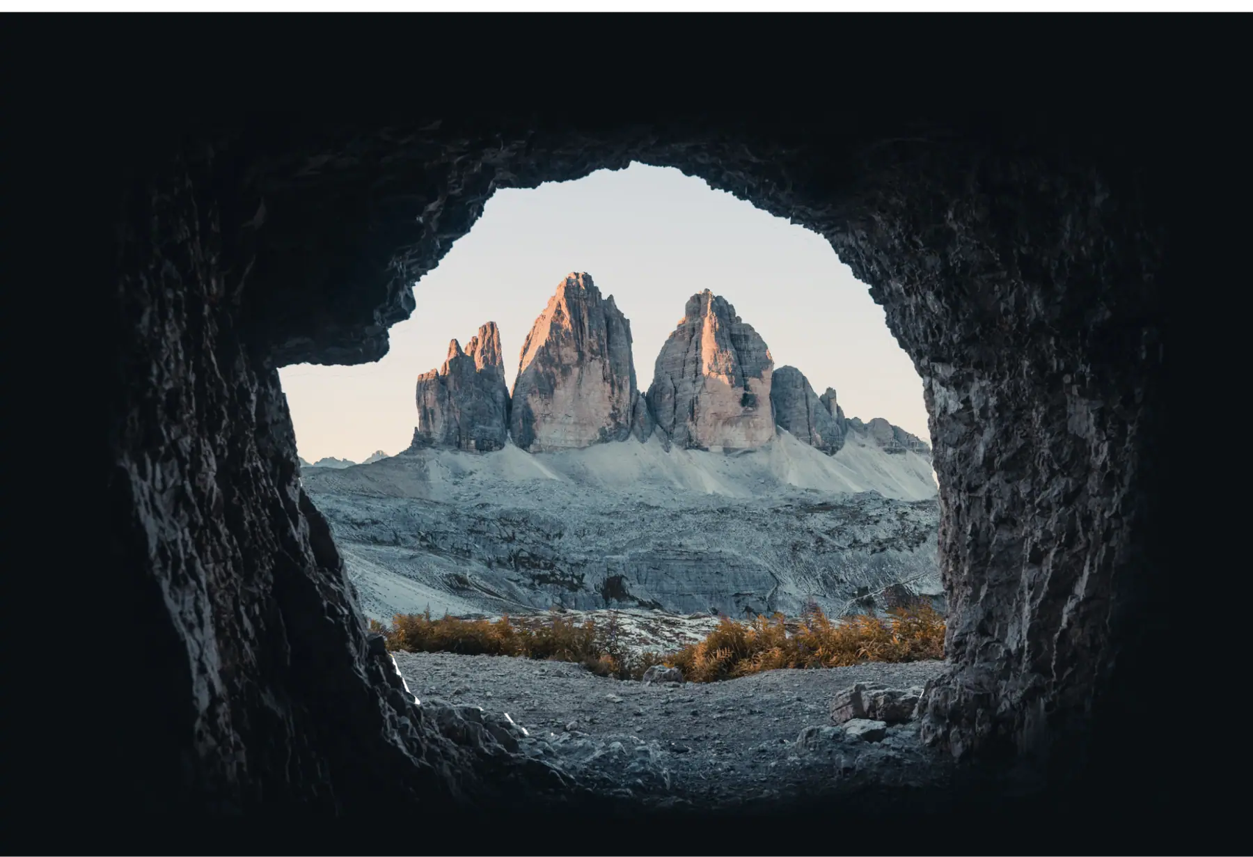 Jagged peaks at dusk, seen through the mouth of a cave