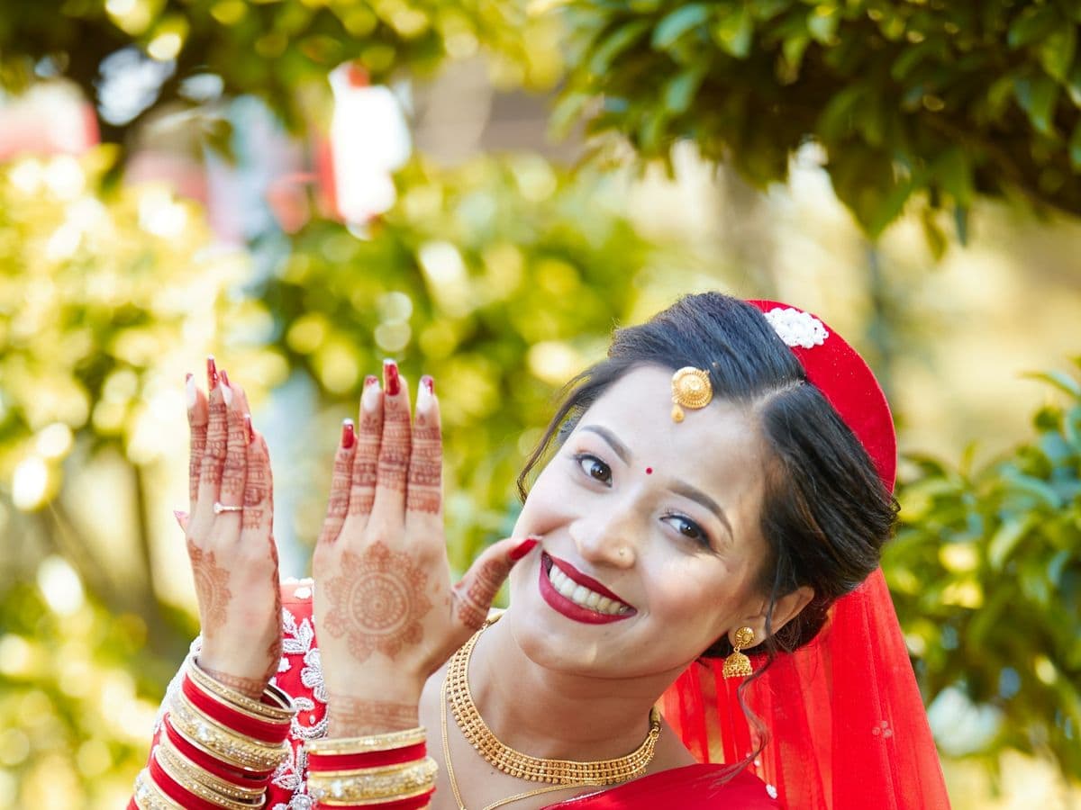 A bride in red laughing with her bangled hands raised