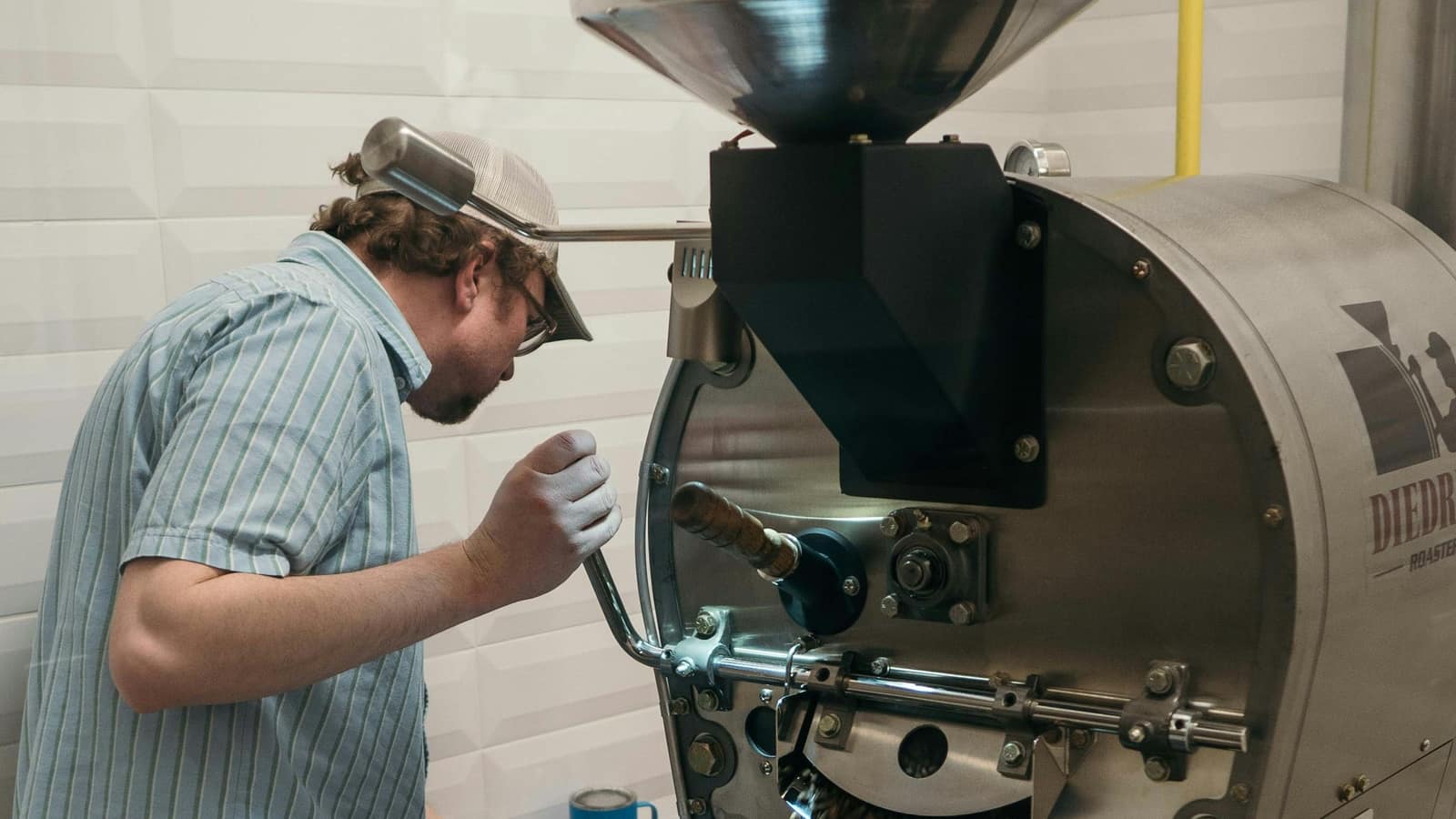A roaster checking the beans as they drop from a coffee roasting machine