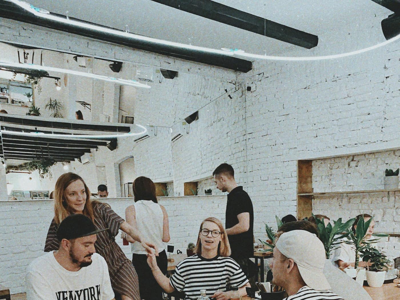 Friends gathered around a wooden table in a bright brewery taproom
