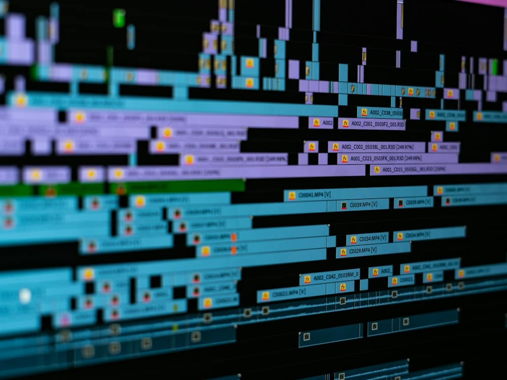 A video editing timeline with colour-coded clips stretching across a dark screen